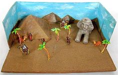 there are many small figurines in the desert with rocks and palm trees around them