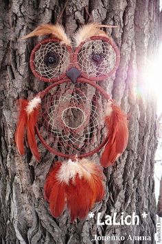 an owl made out of red feathers on top of a tree