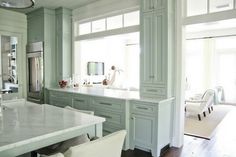 a kitchen with green cabinets and white counter tops