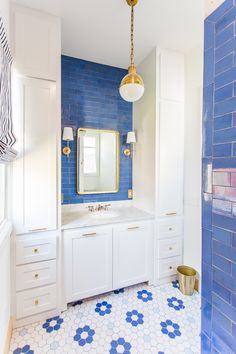 a bathroom with blue and white tiles on the floor, sink and mirror in it