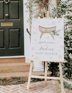 a welcome sign in front of a door with snowflakes on the ground and greenery around it