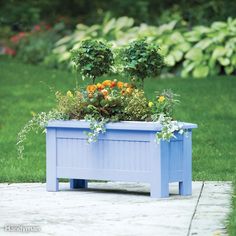 a blue planter filled with flowers on top of a wooden table in the grass