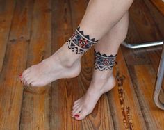 a woman's legs with tattoos on them sitting in front of a wooden table