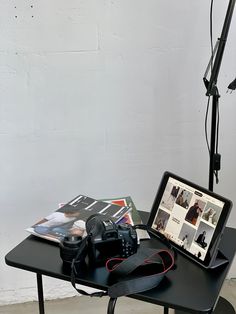 a table with a laptop and camera on it next to a tripod light stand