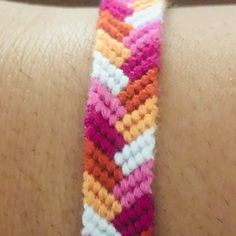 a close up of a person's arm with a bracelet on it that has an orange, pink, and white chevron