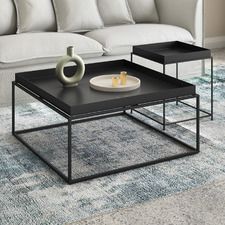 two tables sitting on top of a rug in front of a couch and coffee table