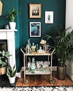 a bar cart with bottles and glasses on it next to a potted palm tree