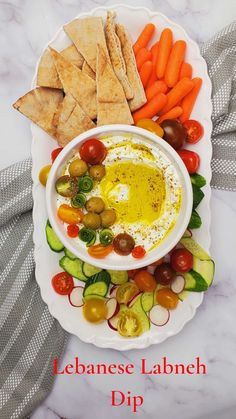 a white plate topped with veggies and crackers next to a bowl of dip