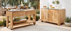 an outdoor dining area with wooden furniture and potted plants on the table, next to a garden