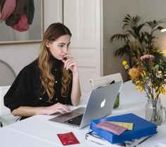 a woman sitting at a table using a laptop computer