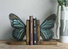 two books are sitting on a shelf next to a vase and butterfly bookends