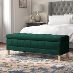 a green bench sitting on top of a rug next to a bed in a bedroom