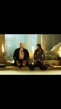 two people sitting on the floor in front of some burning candles and looking at each other