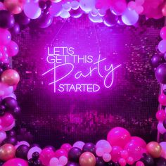 a neon sign that says let's get this party started with balloons and streamers