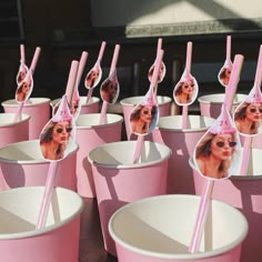 there are many pink cups with pictures on them and straws sticking out of them