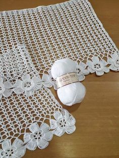 a white crocheted doily and ball of yarn on a wooden table top