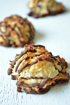 three cookies with chocolate drizzled on them sitting on a white table top