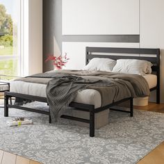 a bedroom with a bed, nightstands and rug on the floor in front of a large window