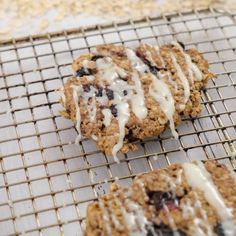 three cookies on a cooling rack with icing drizzled over them and blueberries