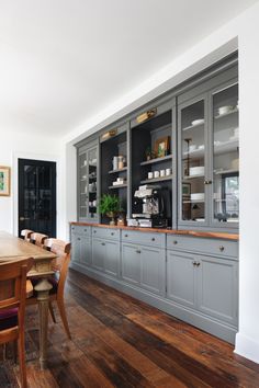 a dining room table and chairs in front of a kitchen with built - in cabinets