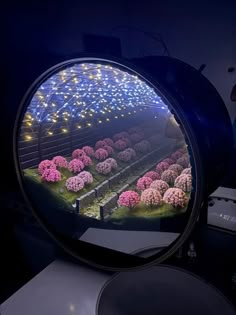 a mirror that is on top of a table with flowers in the reflection and lights behind it