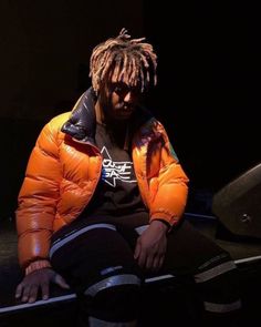 a man with dreadlocks sitting on top of a skateboard in the dark