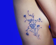 a blue flower tattoo on the back of a woman's right thigh