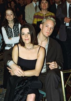 a man and woman sitting next to each other in front of a group of people