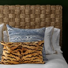 a tiger print pillow on top of a bed with white linens and blue pillows