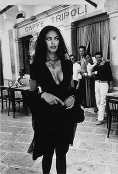 black and white photograph of a woman standing in front of a cafe