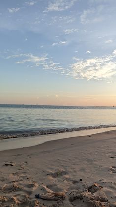 there is a surfboard sitting on the sand at the edge of the water's edge