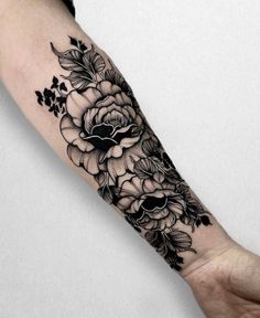 a black and white flower tattoo on the left arm, with flowers in it's center