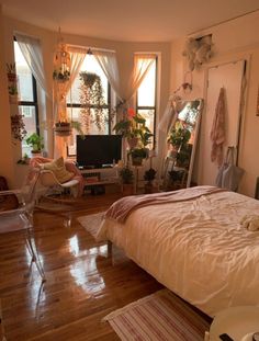 a bedroom with hardwood floors and lots of plants in the window sill, along with a bed