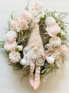 a wreath with a doll and flowers on it