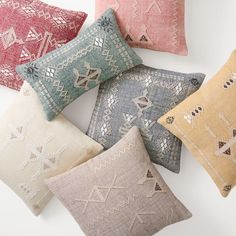 six different colored pillows on a white surface