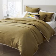 a bed with brown sheets and pillows in a bedroom next to a white headboard