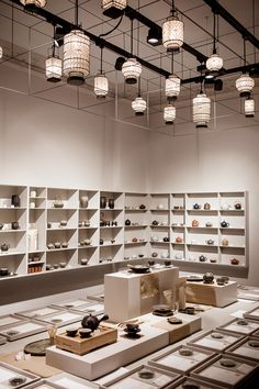 a room filled with lots of white shelves and lights hanging from the ceiling above them