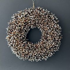 a wreath made out of pine cones hanging from a chain on a gray background with space for text