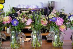 several vases with flowers in them sitting on a table next to eachother