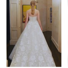 a woman in a white wedding dress is walking down the hall with her back to the camera