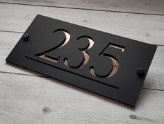 a metal house number sign on a white wood floor with the numbers 350 and 53