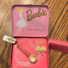 two pink tins with various items in them sitting on a table next to each other