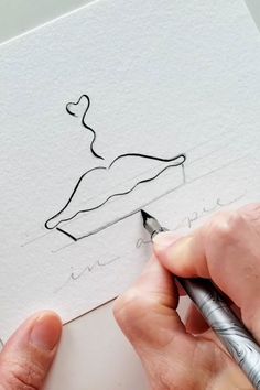 a person is drawing on paper with a pen and inking the image in black