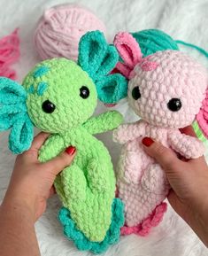 two crocheted stuffed animals are being held by someone's hand on a white blanket