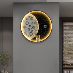 a clock that is on the wall next to a table with a plant in it