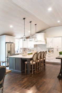 a large kitchen with white cabinets and wooden flooring, along with an island in the middle