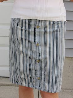 a woman wearing a white top and blue striped skirt with her hands in her pockets