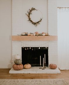 a fireplace with candles and pumpkins on the mantle