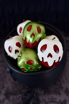 some green and red candy skulls in a black bowl