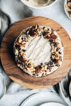 a cake sitting on top of a wooden platter covered in pecans and nuts